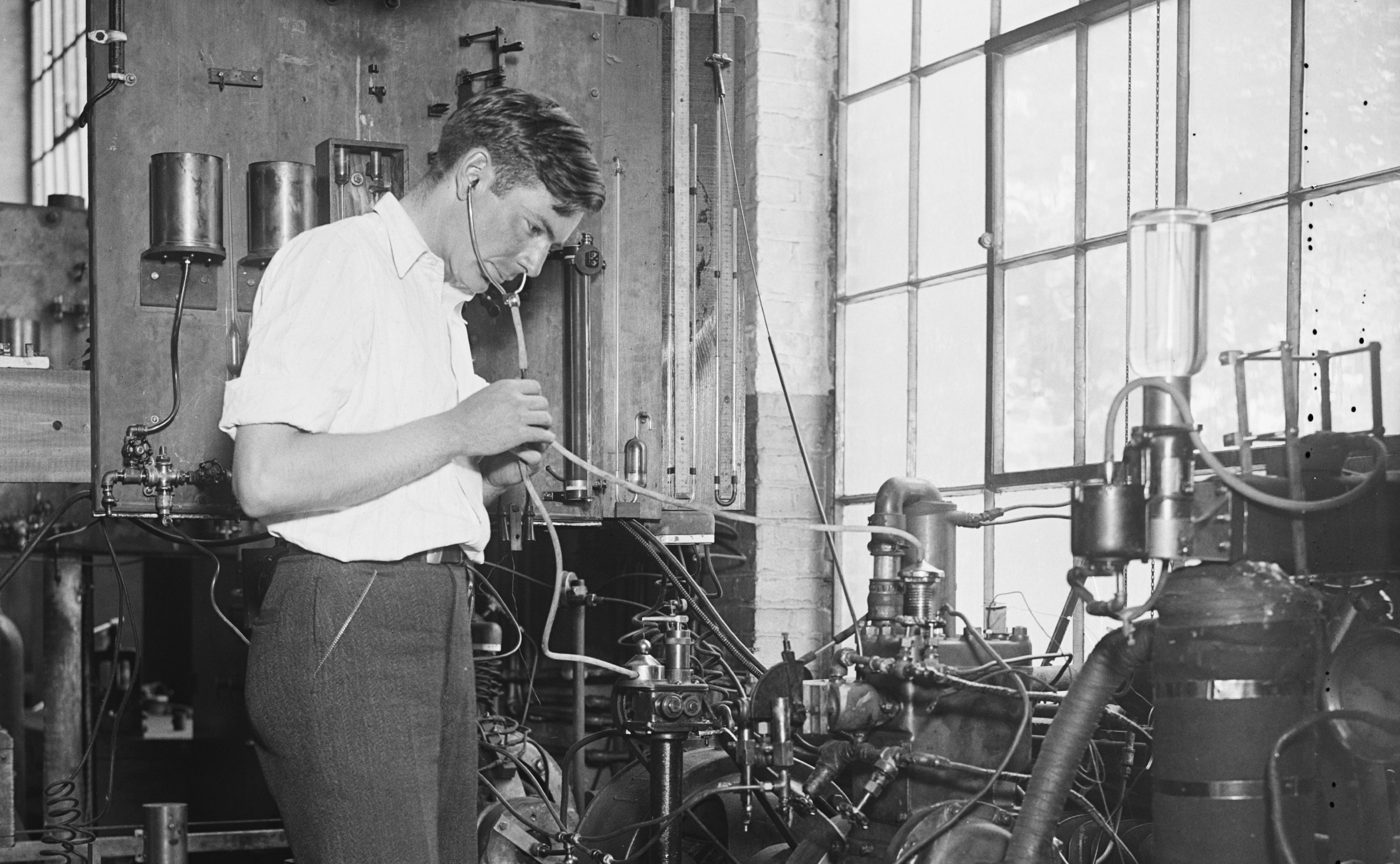 A fuel expert listens to an engine with a stethoscope.